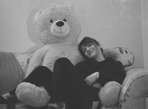 Woman with a soft smile chilling with a giant teddy bear