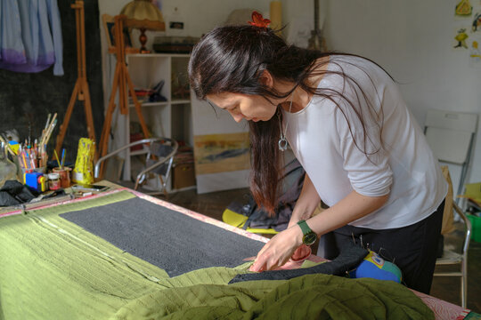 The woman is cutting fabric on the table 