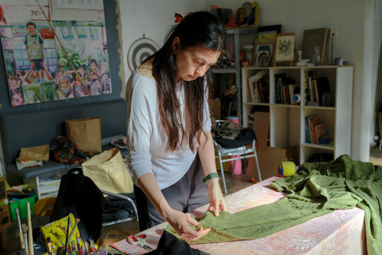 The woman is cutting fabric on the table 
