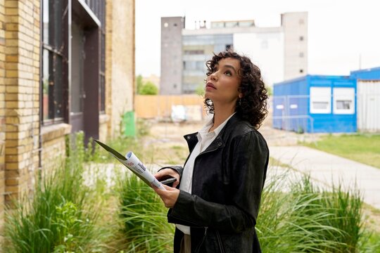 Woman Assesses Urban Building Project at Construction Site