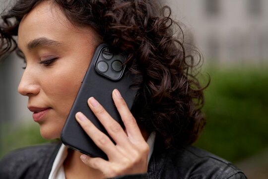 Woman With Curly Hair Talking on Smartphone Outdoors in City