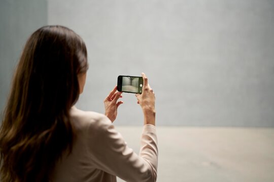 Woman takes a smartphone picture in a minimalistic space