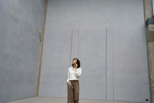 Woman explores minimalistic interior in modern building while calling