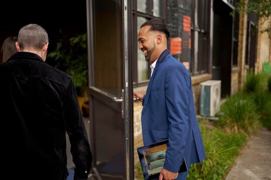 Real Estate Businessman Entering a Building With a Tablet in Hand