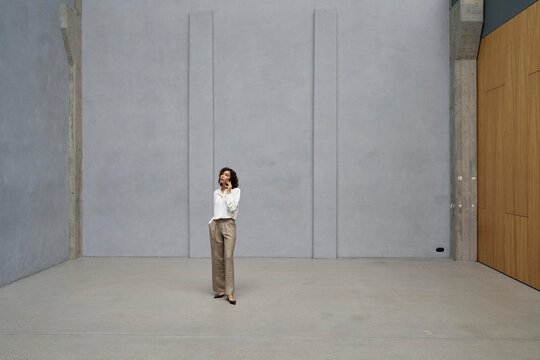 Woman Standing in Minimalist Space With Gray Walls and Natural Light