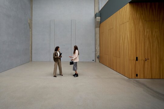 Two women converse in a modern spacious indoor setting