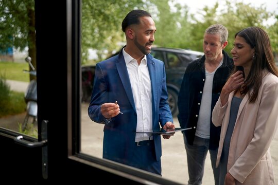 Real Estate Agent Discusses Property With Potential Buyers Outdoors