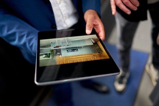 Person shows digital real estate presentation on tablet 