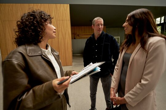 Three individuals discuss casually in a contemporary indoor space