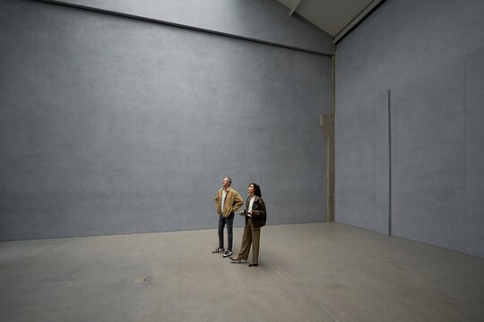 Visitors observe architecture in a minimalistic loft like space