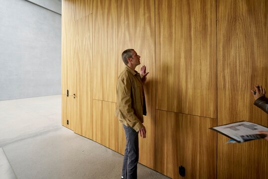 Man Examines Wooden Wall in Modern Interior Space