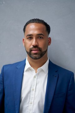 Professional man in a blue suit standing against a wall