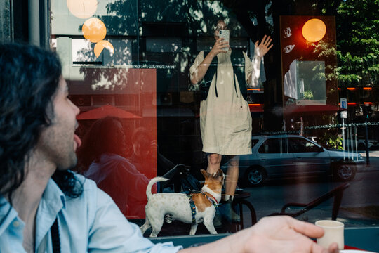 Person Enjoying a Coffee While Taking a Selfie Through a Window