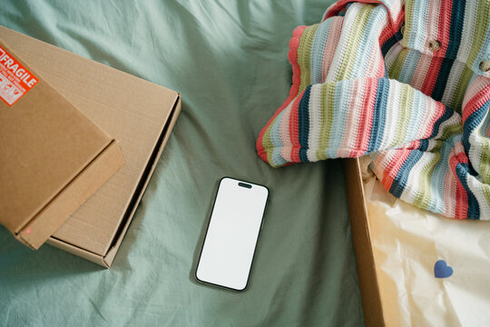 A mobile phone with white screen next to the parcels