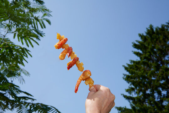 Hand Holding Grilled Shrimp Skewer