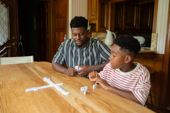 Father and son enjoying a game of dominoes at home