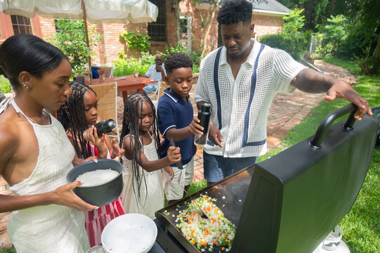 Family standing around grill cooking together