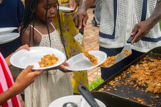 Dad serving daughter fried rice straight from grill