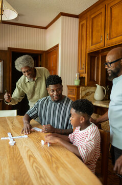 Family enjoying a game of dominoes at the kitchen table 