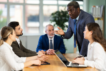 Adult man manager holding business meeting with colleagues at table in office