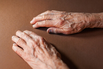 Elderly hands resting on a table in a warm indoor environment