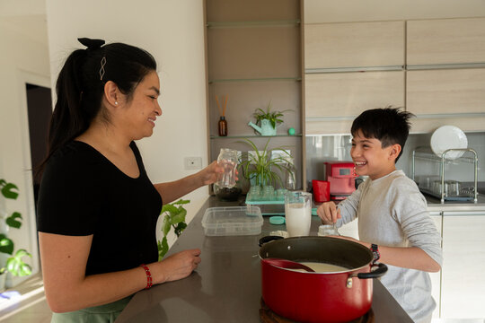 Mother and son prepare yogurt together in a modern kitchen