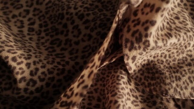 Closeup video of piece of clothes made of soft woollen leopard print fabric. Appreciating pleasant texture of high quality textile for clothes. Soft and cosy textile. Trendy clothes fabric for winter 