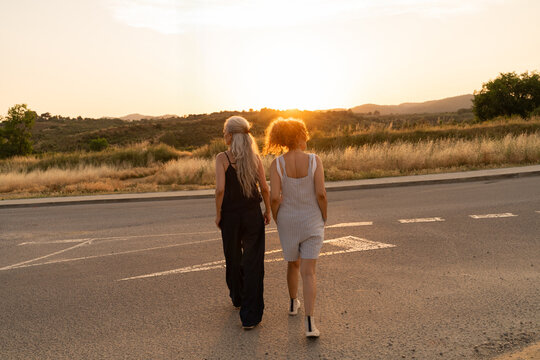 Women walking sunset road