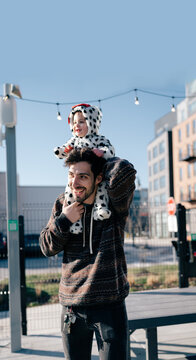 A father carries his son in a dog costume on his shoulders