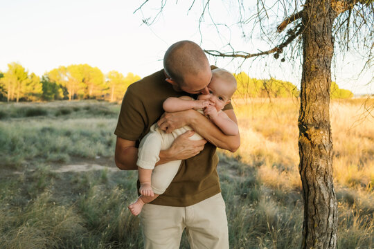 Father holding baby in a beautiful outdoor setting during sunset