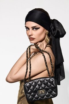 Fashion Portrait of Woman in Gold Dress and Black Bandana Sitting on C