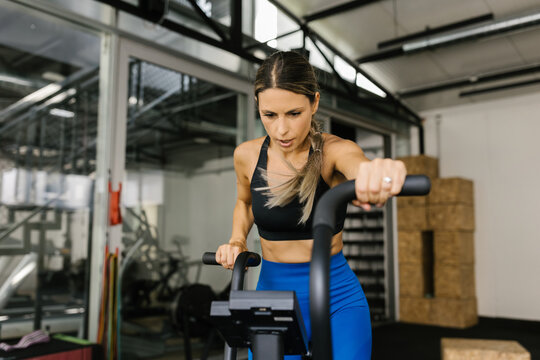 Woman Exercising on Elliptical Machine in Modern Gym