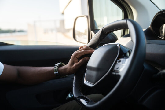 Man&acirc;s hand resting on steering wheel inside car
