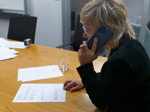 Person Speaking on Phone While Reviewing Documents at Office Table