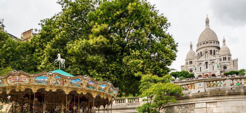France, Paris, Montmartre.  Sacr&eacute;-C&oelig;ur Basilica high up on the Butte Montmartre, with carousel in the foreground.