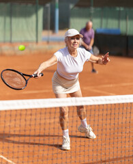 Active elderly couple playing lawn tennis outdoors. Senior husband and wife spend weekends together and play sports