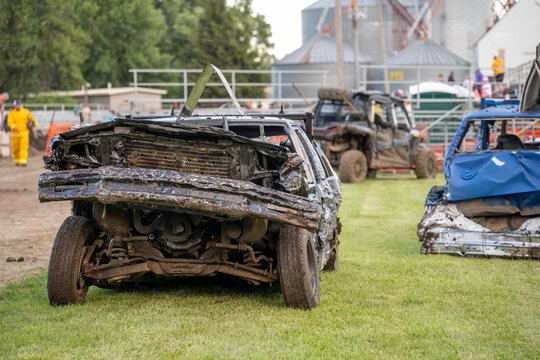 Old cars are ready for a demolition derby event at a fairground in summer at a local community gathering near the grandstand area
