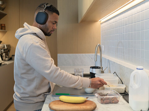 Man Preparing a Protein Shake in a Kitchen With Headphones On