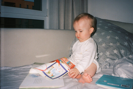 Toddler on bed flipping through picture book before bedtime - film