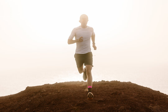 Backlit view of a trail runner trekking across rocky ground