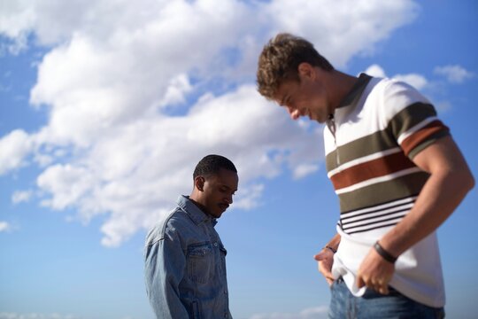 Two friends share a moment outdoors under a blue sky