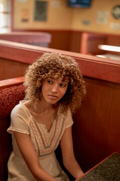 Curly haired woman sitting in a cozy restaurant booth