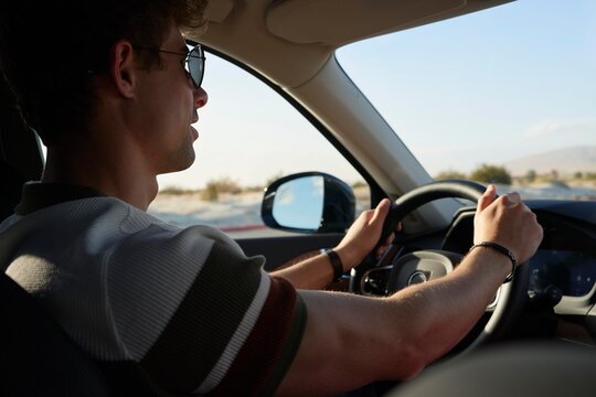 Man Driving a Car on a Sunny Day in the Desert Landscape