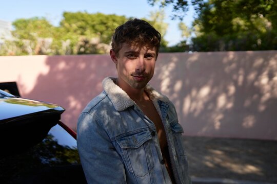 Man Posing Outdoors Near his New Car on a Sunny Day