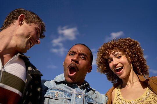 Friends Celebrating Outdoors Under a Clear Sky With Joyful Expressions