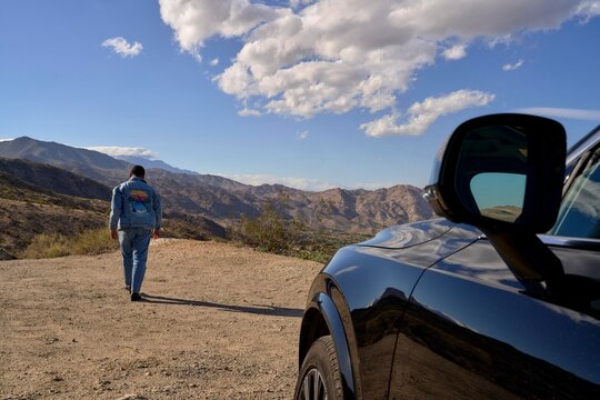 Man Walks Through Desert Landscape With Mountains in the Background