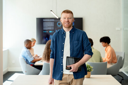 Smiling businessman holding tablet with coworkers in office
