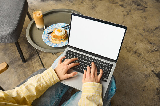A woman uses a laptop with white screen