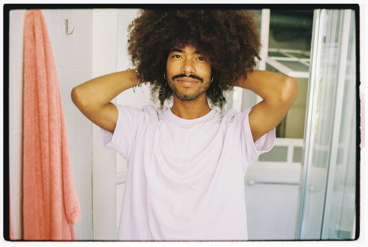 Man Styling Curly Hair in Bathroom