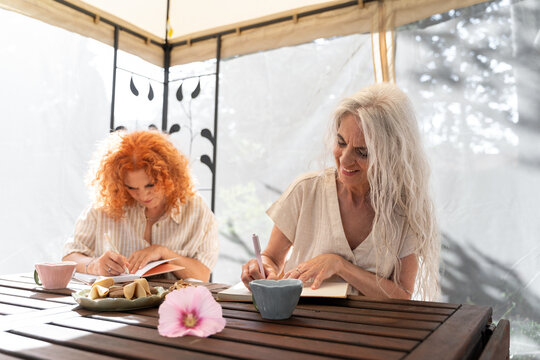Two women journaling outdoors